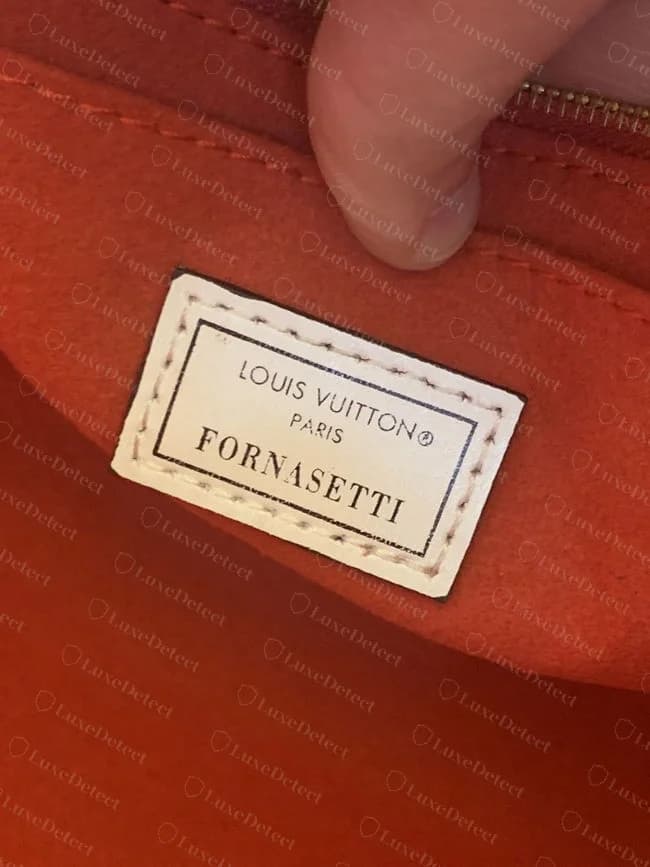 Interior tag on a confirmed counterfeit OnTheGo in a Fornasetti-print canvas, showing a printed rectangle tag design that does not match how genuine Louis Vuitton collaboration tags are produced