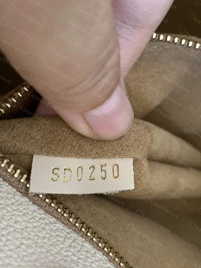 Authentic Louis Vuitton date code stamp inside an OnTheGo, reading a valid two-letter-plus-four-digit format on a small leather tab
