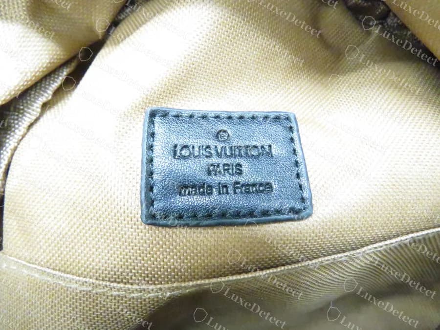 Counterfeit Palm Springs Mini interior patch: the I in LOUIS is malformed so it reads close to LOU'S VUITTON, heavy uneven letters, beige plain-weave lining