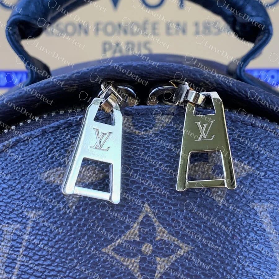 Counterfeit full-size Palm Springs: the two main zip pulls are visibly different metal finishes, one pale silver-toned and one gold, on the same bag