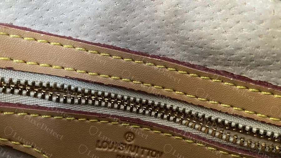 Fake Papillon: a leather strip with embossed LOUIS VUITTON text stitched along the zip edge, over a perforated beige lining