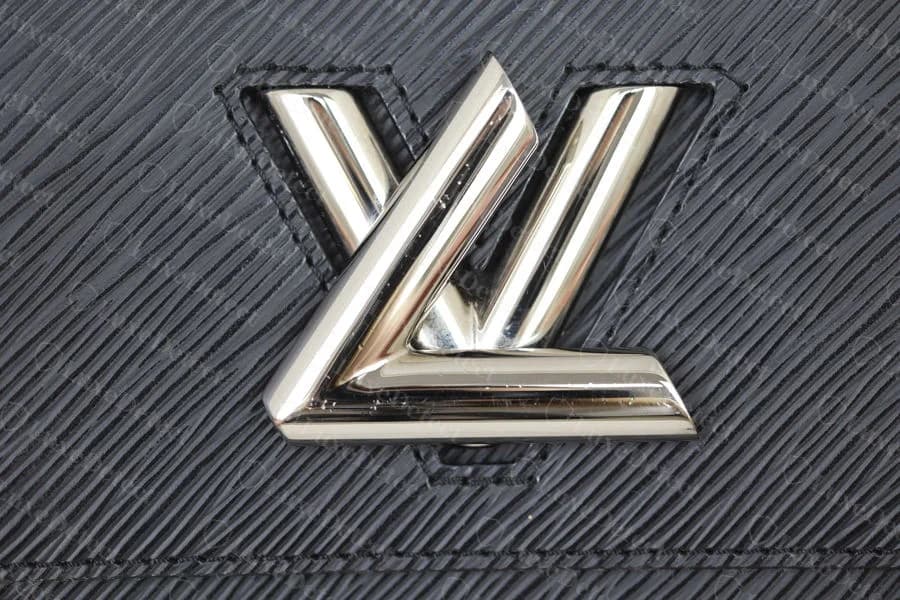 Authentic Louis Vuitton Twist clasp — the L and V meet at a crisp, symmetrical seam, sitting flush with an even gap around the die-cut window
