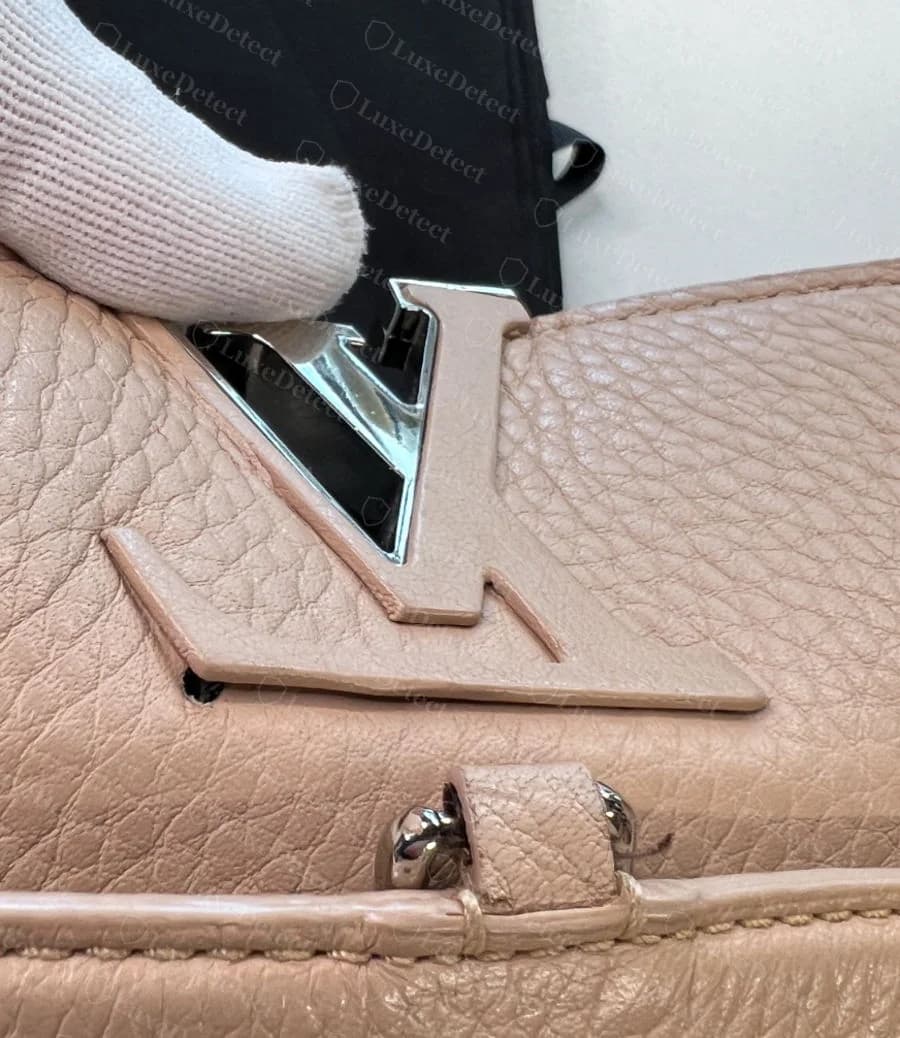 Genuine LV turn-lock clasp on a Capucines flap, gold-tone metal set into pebbled Taurillon leather with sharp, evenly plated letterforms