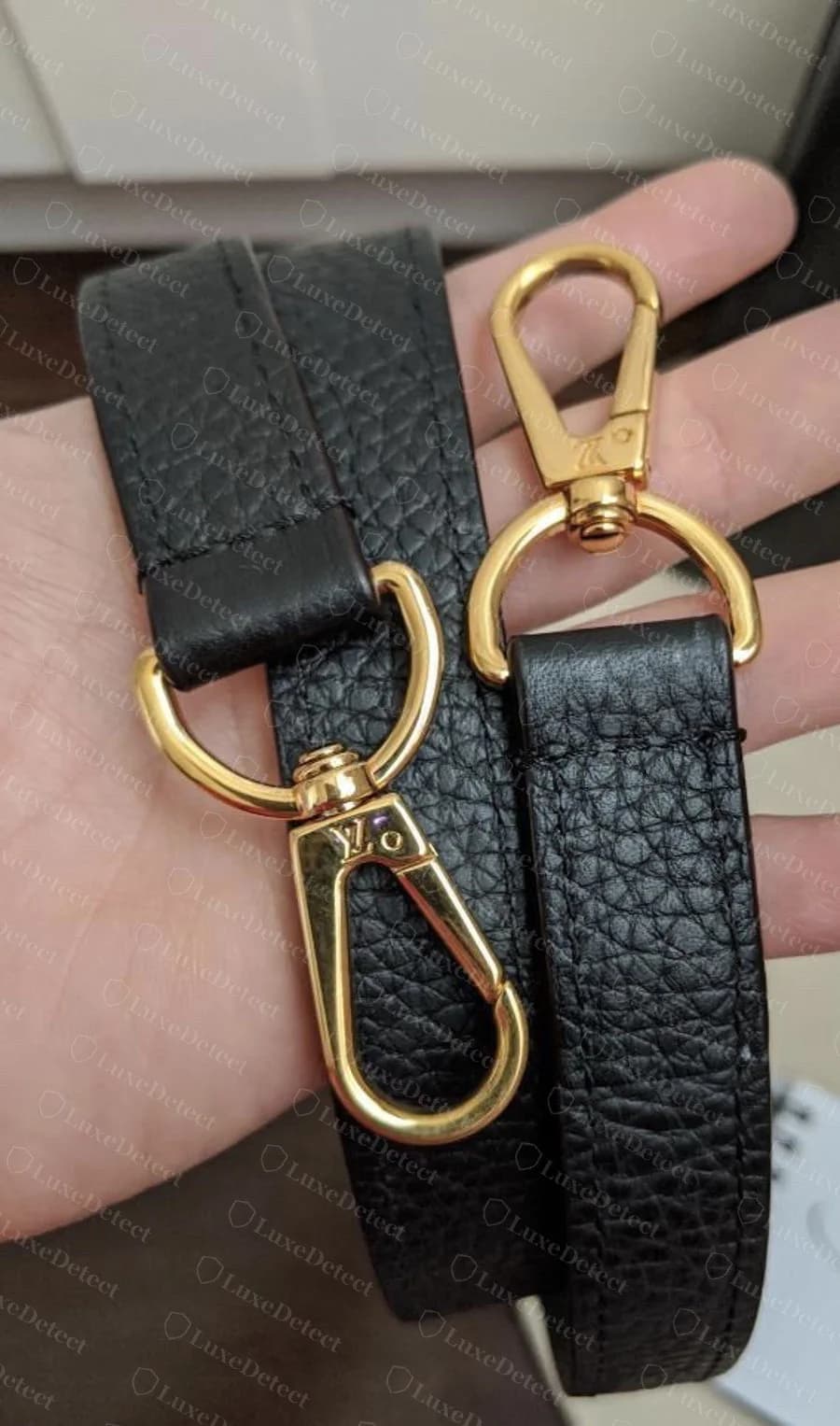 Genuine gold-tone lobster-clasp hardware on a Capucines strap tab, stamped with a small "LV" mark near the pivot, shown here to compare plating consistency against the flap clasp above