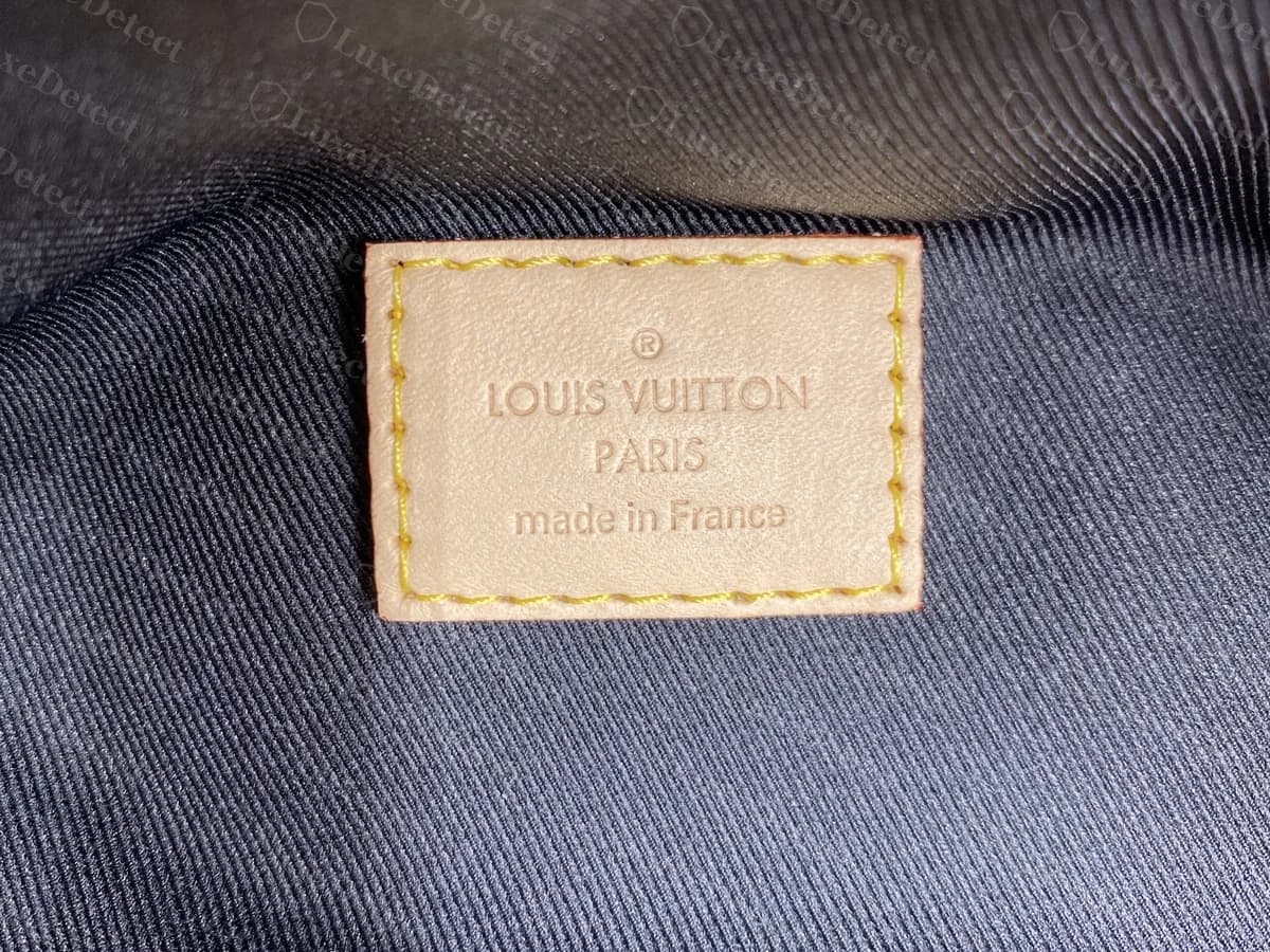 Echte Bumbag-Innenlasche aus cremefarbenem Leder mit gelben Nähten: Registered-Zeichen, LOUIS VUITTON, PARIS und made in France, auf marineblauem gerippten Futter