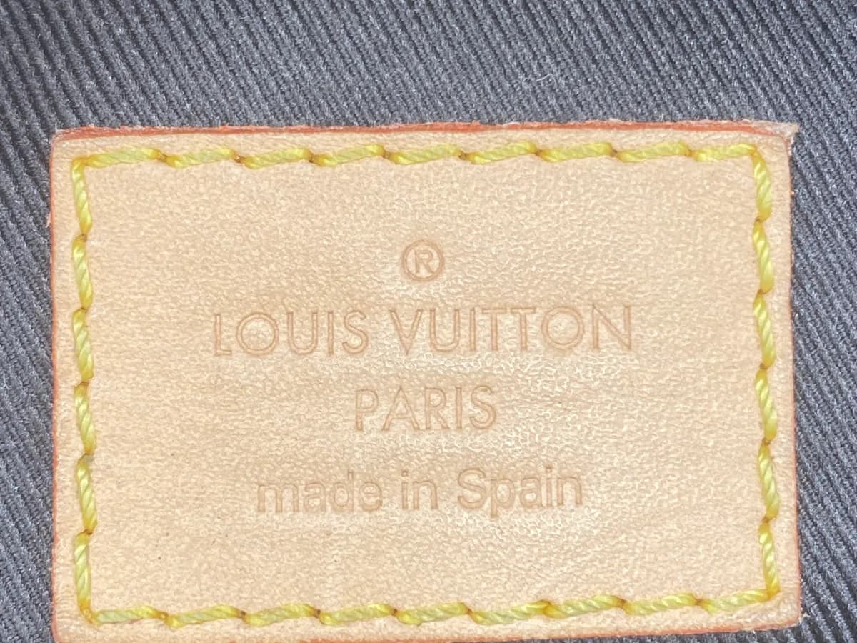 Languette intérieure d'un Bumbag authentique indiquant LOUIS VUITTON PARIS made in Spain, avec coutures jaunes, sur une doublure côtelée bleu marine