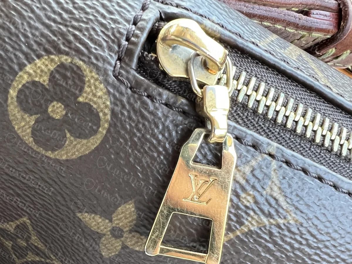 Tirette d'un Bumbag authentique : un curseur en laiton avec une tirette ajourée et haute portant un monogramme LV, vue sur la toile Monogram marron