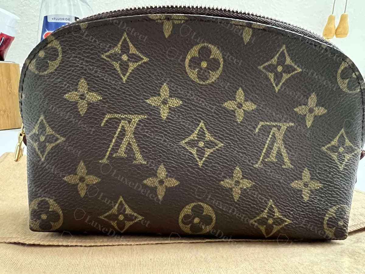 Cosmetic Pouch Monogram original visto de frente: un neceser de media luna con cremallera, borde superior curvo y motivos del monograma espaciados de forma pareja
