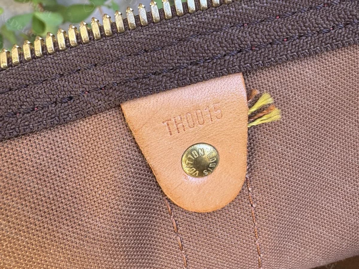 Echte Louis-Vuitton-Datecode-Lasche eines Murakami Cherry Keepall 45: TH0015 in eine helle Lederlasche über einem Messingniet gestempelt
