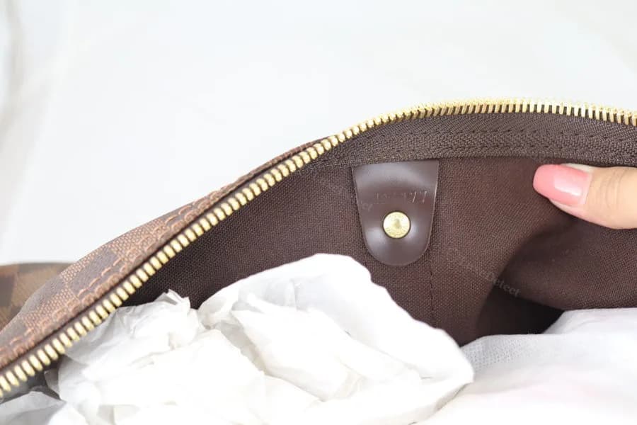 Authentic Louis Vuitton date code stamp inside a Damier Ebène Keepall — clean, legible two-letter-plus-four-digit format