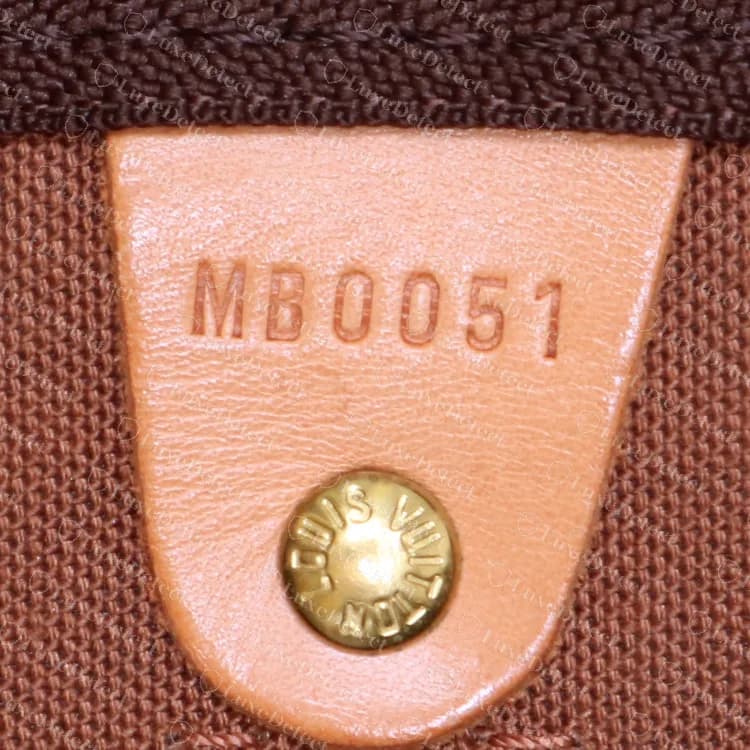Lengüeta del código de fecha de un Louis Vuitton Keepall Bandoulière 45 original: MB0051 estampado encima de un remache, mes 05 y año 01, es decir, mayo de 2001