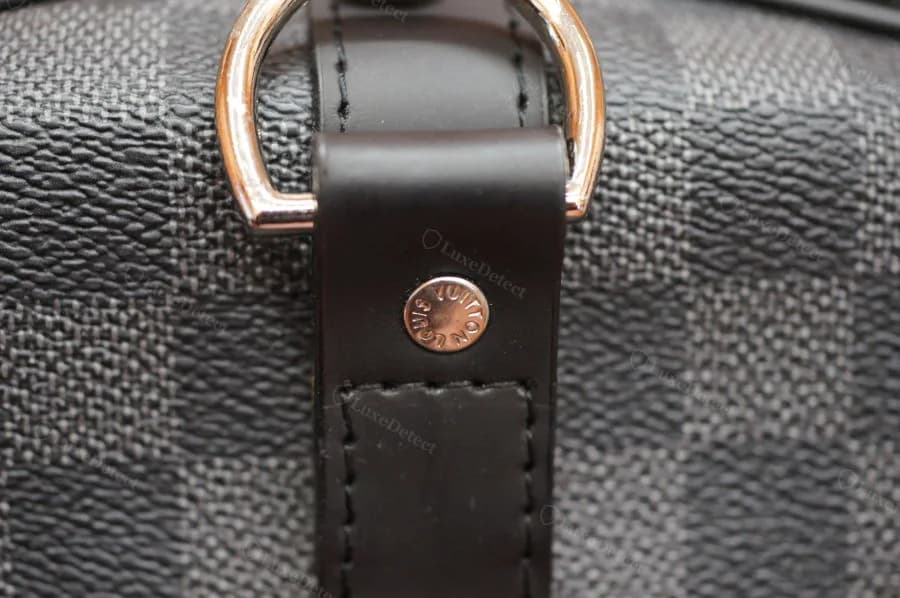 Hardware detail from a counterfeit Keepall in our archive — the D-ring rivet stamp is present but should be weighed with the leather and interior checks, not read alone