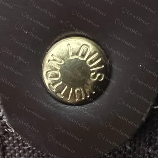 Rebite original de um Keepall na etiqueta interna Damier Ébène: LOUIS VUITTON uniformemente espaçado em todo o anel, com um centro limpo e liso