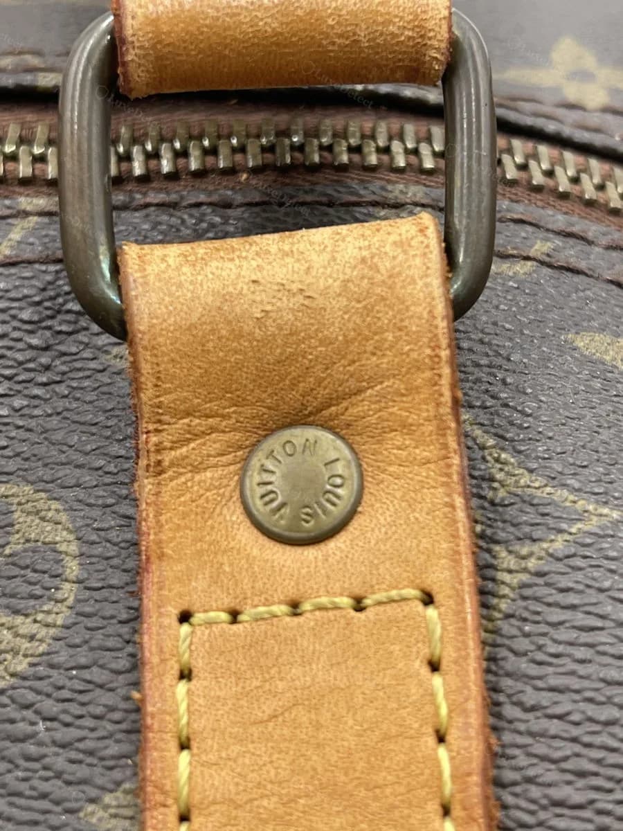A Keepall ruled counterfeit in our archive — the vachetta tab and rivet strike look close to genuine at this angle, illustrating why this check alone is not decisive