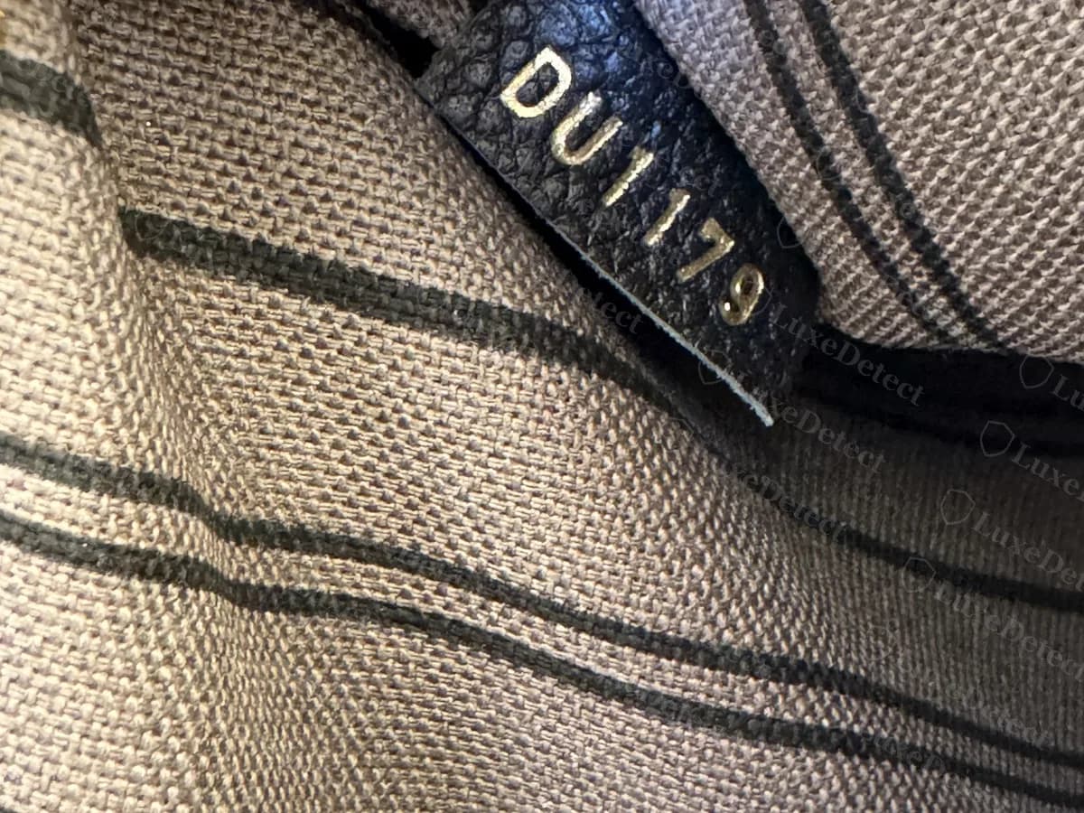 Genuine date code on a Metis: "DU1179" stamped on a small black leather tab tucked into the striped lining
