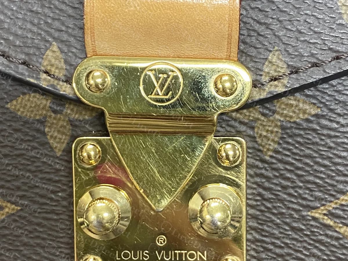 Genuine S-lock on Monogram canvas: an LV in a circle on the top plate, two domed studs and "LOUIS VUITTON PARIS" stamped on the base plate, with a vachetta tab above