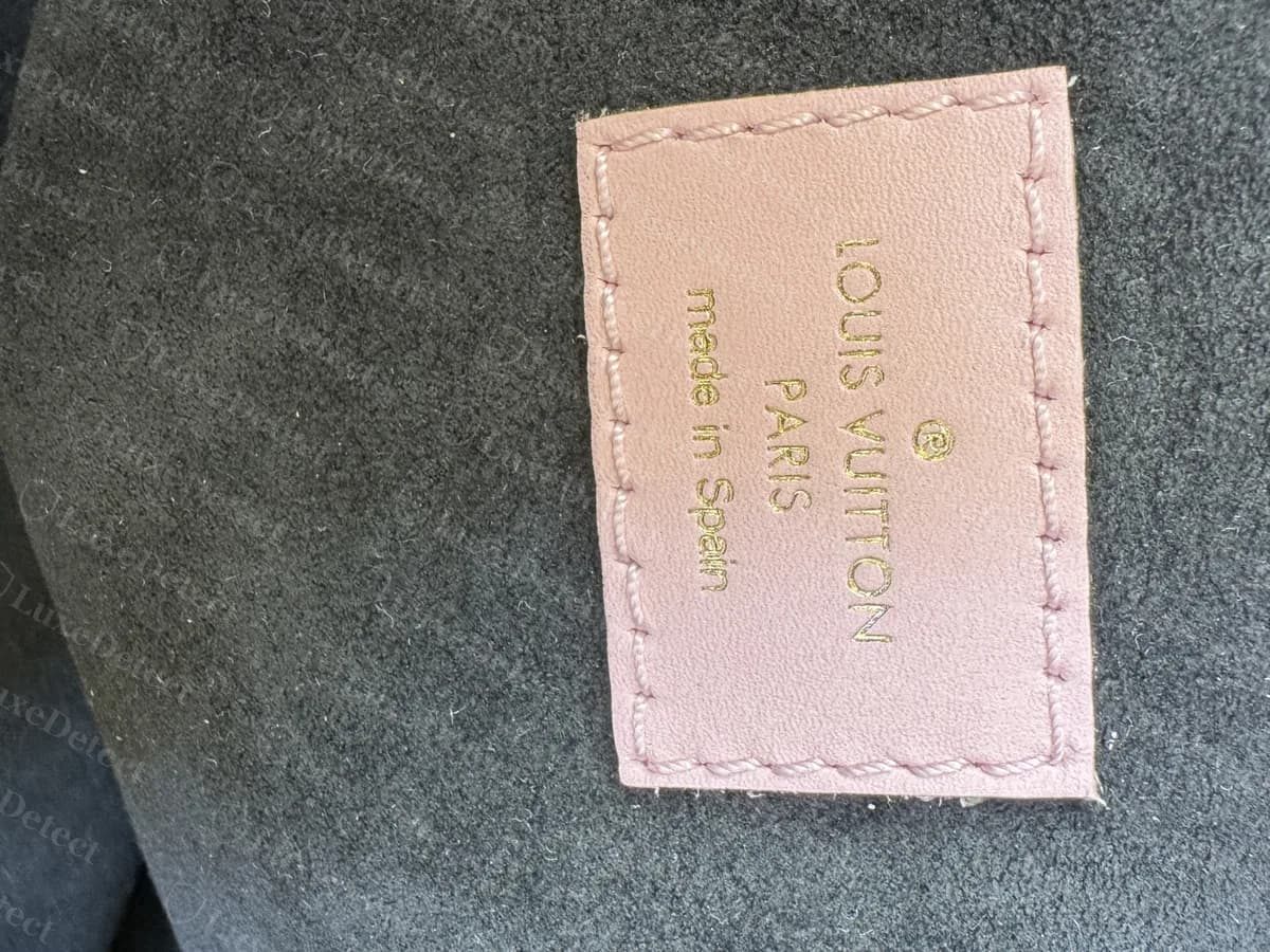 Echte Tasche aus unseren Bestellungen der Mikrochip-Ära: ein rosafarbenes Lederetikett mit der Aufschrift LOUIS VUITTON PARIS made in Spain, in ein graues Futter eingenäht