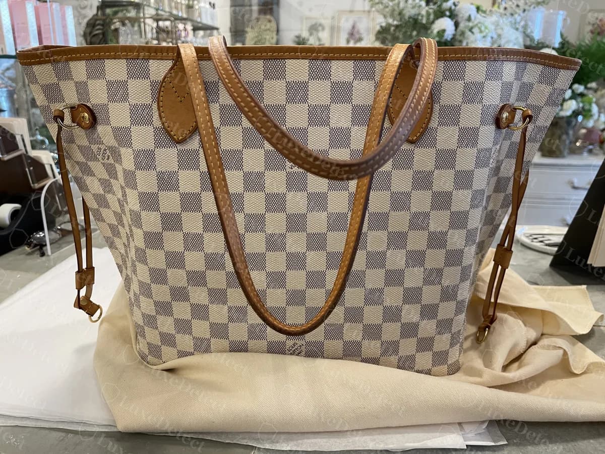 Neverfull MM Damier Azur original vista de frente: um corpo trapezoidal macio, duas alças de vachetta e cordões laterais que ajustam a bolsa