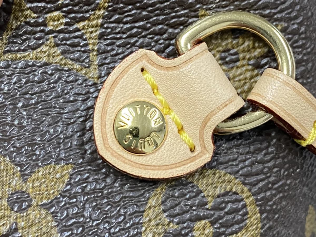 Lengüeta del cordón lateral de una Neverfull original: una lengüeta de vachetta sujeta con un remache con LOUIS VUITTON estampado, con una argolla de latón para el cordón