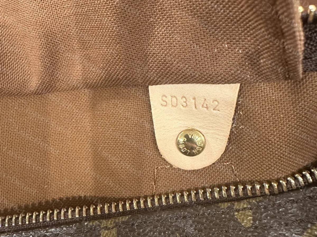 Lengüeta interior de un Speedy Monogram original: el código de fecha SD3142 estampado en una lengüeta de vachetta clara con un remache estampado, sobre el forro de lona marrón