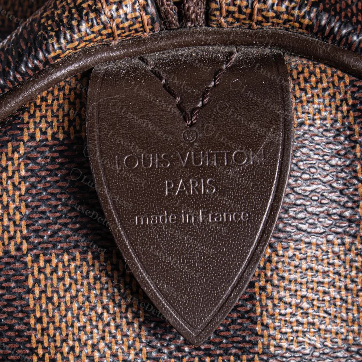 Echte Heißprägung der Speedy-Seitenlasche auf Damier Ebène: die eingetragene Marke, "LOUIS VUITTON", "PARIS" und "made in France", unter einem genähten V ins Leder der Lasche gepresst