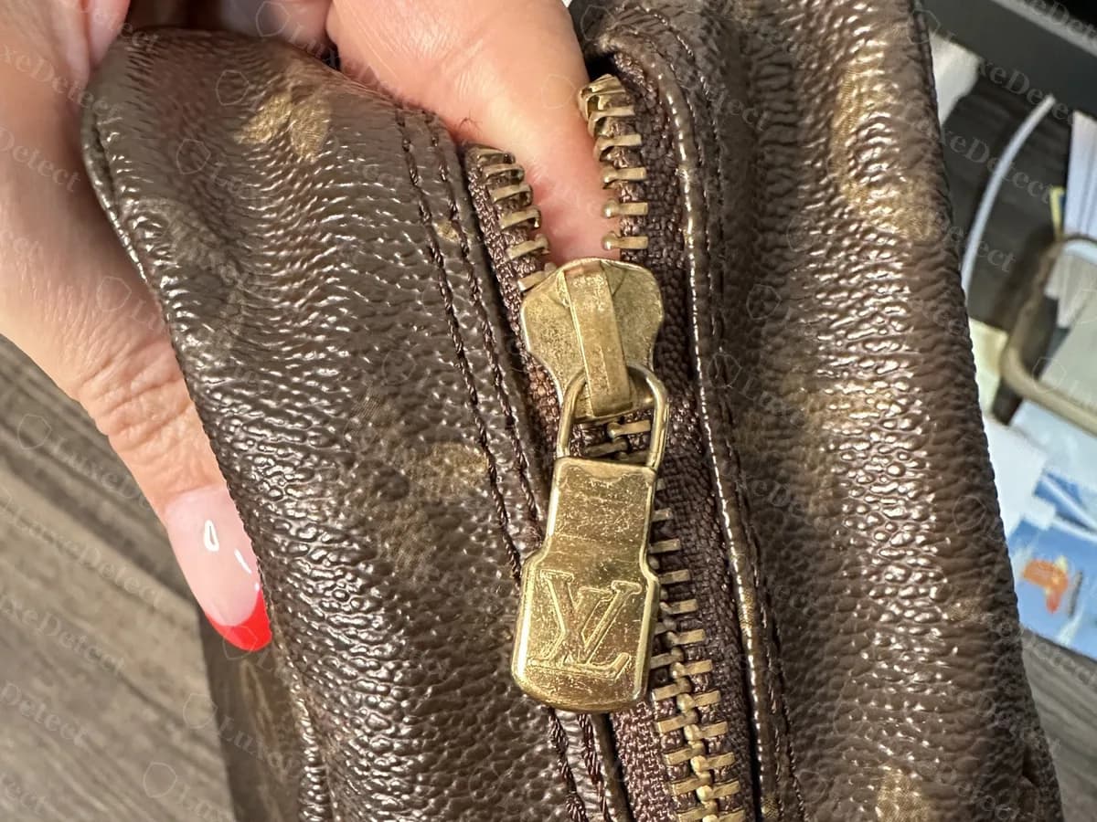 Zieher am Reißverschluss einer echten älteren Trousse 28: ein Messing-Schieber und Zieher mit einem LV-Monogram, an einem gebrauchten Monogram-Etui