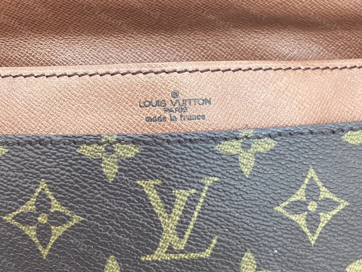 Intérieur du rabat d’une ancienne pochette Monogram : LOUIS VUITTON PARIS made in France estampillé en lettres fines et sombres sur du cuir marron, sous la toile monogramme