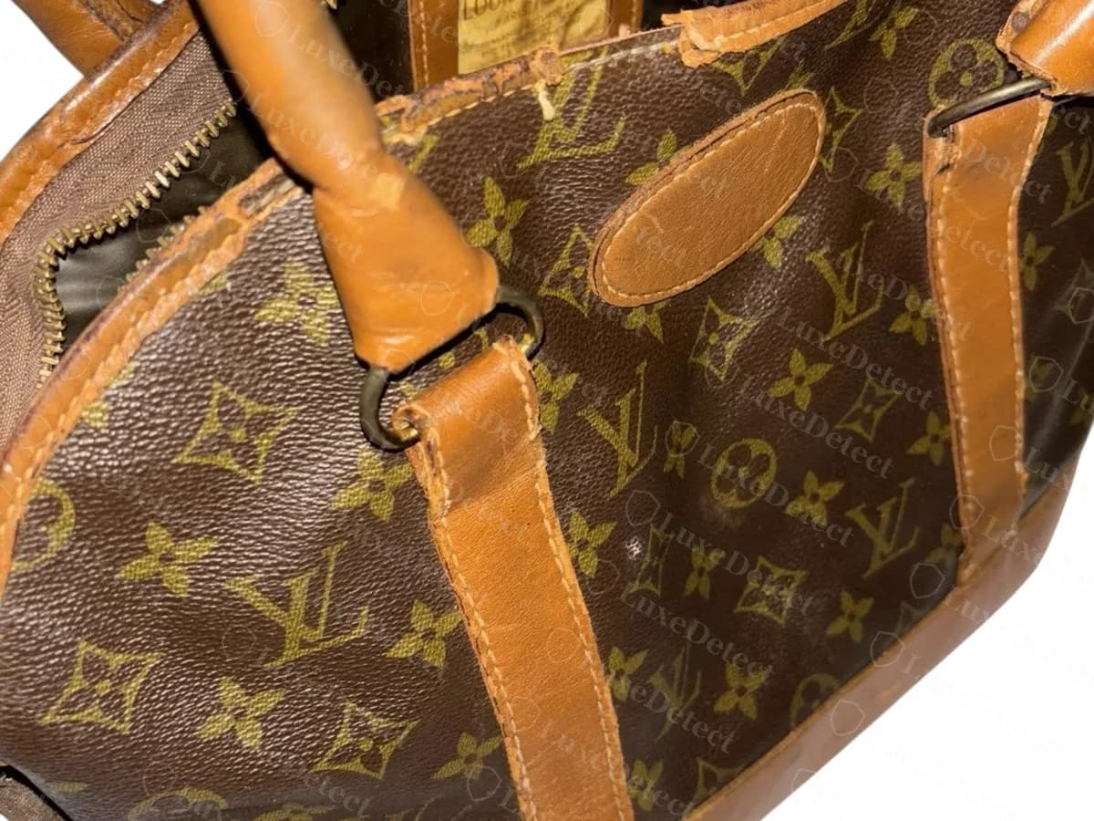 El mismo bolso antiguo desde otro ángulo: una etiqueta cosida en el interior de la parte superior, un parche ovalado en el frente y asas de vachetta desgastadas
