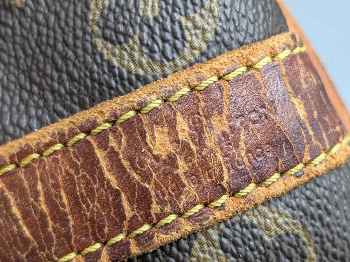 Bandoulière en vachetta très usée sur un ancien sac Monogram : cuir craquelé et très foncé, coutures jaunes encore intactes et estampille à peine lisible