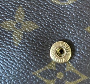 Genuine LV engraved snap hardware — bright, even gold plating with no tarnish, crisp "LOUIS VUITTON" lettering cut cleanly into the metal