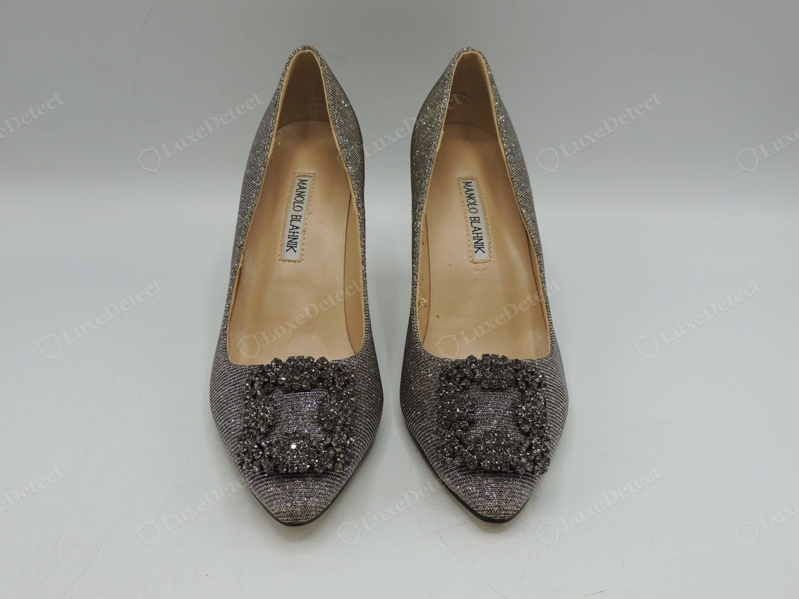 Boucle Hangisi contrefaite Manolo Blahnik — une paire de faux avec des « cristaux » gris fumé ternes qui manquent d'éclat, et une étiquette de semelle intérieure de travers dans son logement