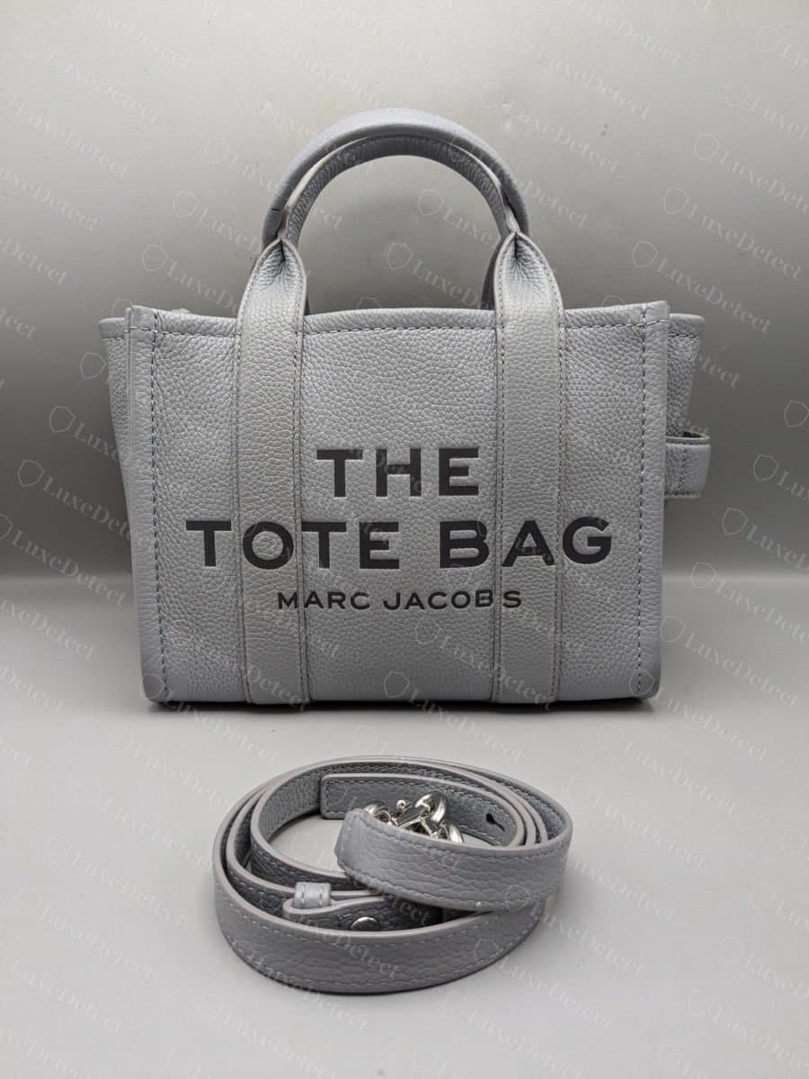 Genuine Marc Jacobs The Tote Bag front logo: thin, evenly spaced "THE TOTE BAG / MARC JACOBS" lettering on a straight baseline