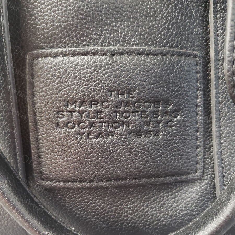 Marquage de la pièce de cuir intérieure d'un faux Marc Jacobs The Tote Bag : lettrage peu profond aux bords doux dans le contour cousu