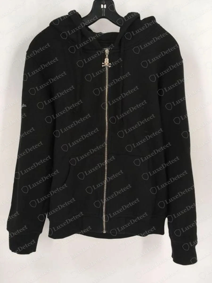 Echter schwarzer Mastermind Japan Zip-Hoodie mit durchgehendem Reißverschluss auf einem Bügel, Vorderansicht, mit einem Metallschieber in Form eines Totenkopfs mit gekreuzten Knochen und einem kleinen weißen Druck am linken Ärmel