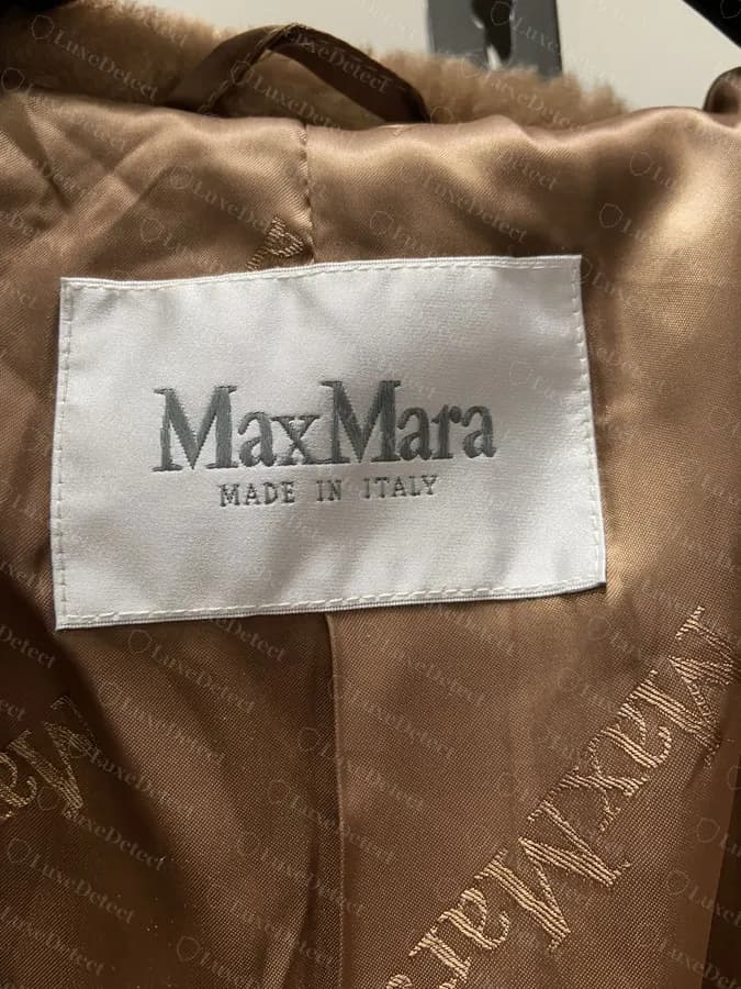 Authentic interior label and lining on a MaxMara Teddy Bear coat; the self-jacquard "MaxMara" pattern is woven into the satin, not printed.