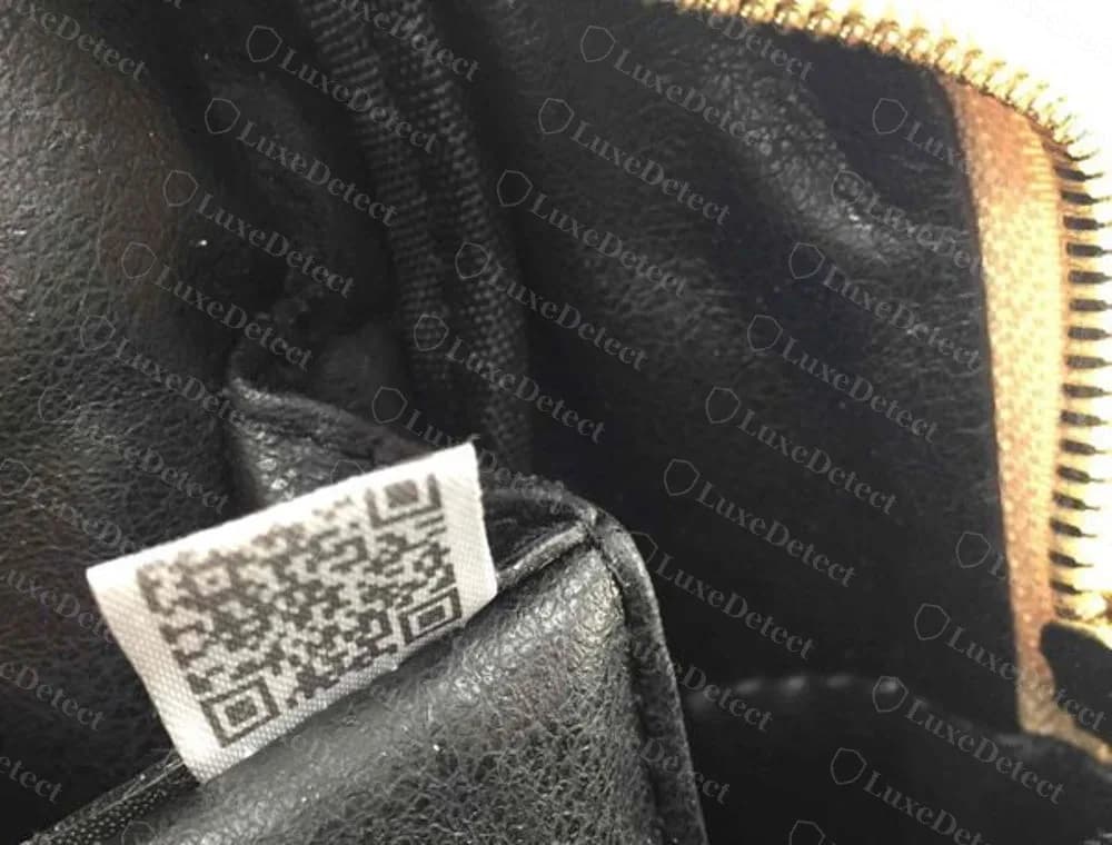 Interno di una borsa MCM contraffatta con un cartellino adesivo con codice QR cucito nella cucitura al posto del testo stampato