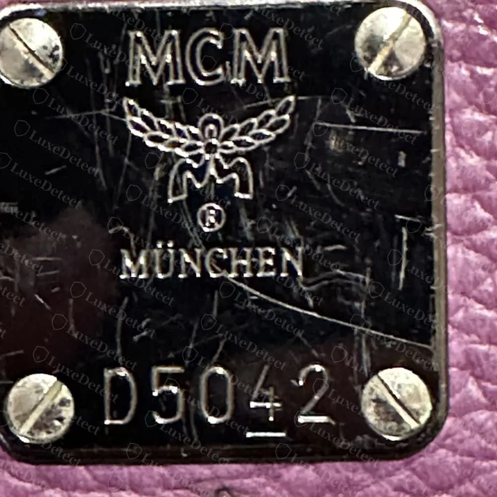 Placca MCM originale color canna di fucile su pelle viola con numero di serie D5042 e una sottolineatura sotto il 4