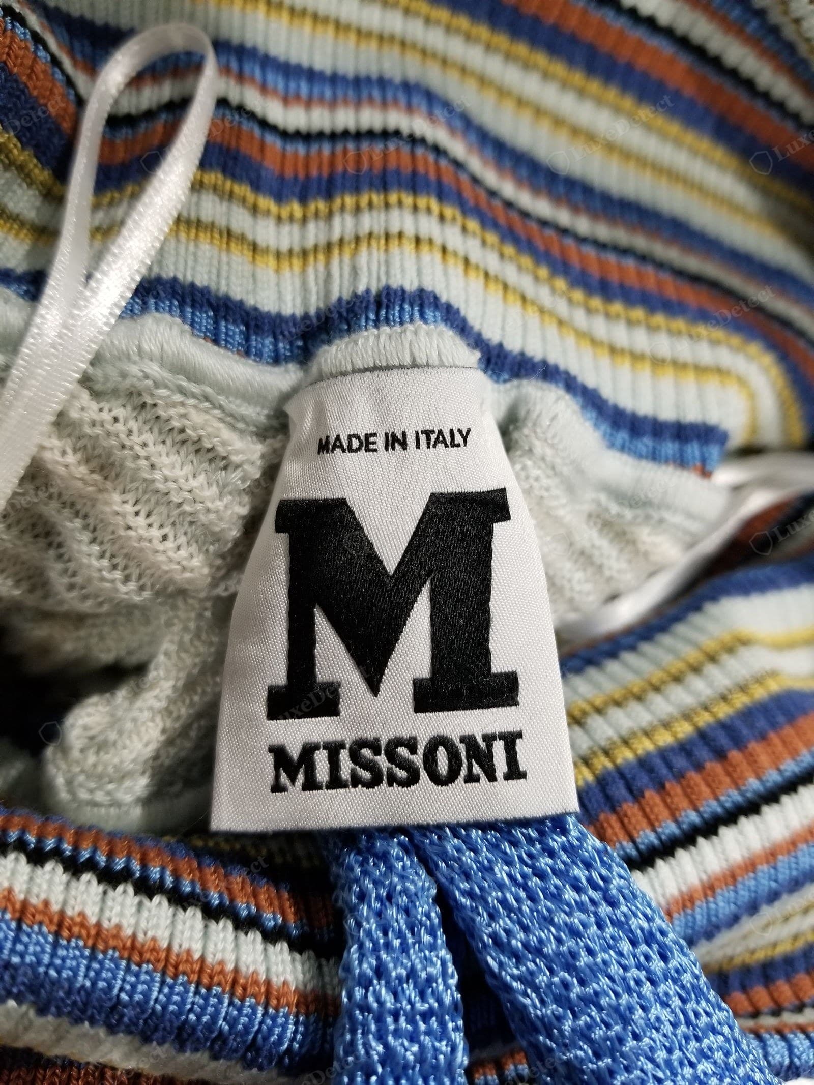 Genuine M Missoni label — the diffusion-line label, a bold "M" over "MISSONI" with "MADE IN ITALY" above, woven on white and sewn into a multi-colour striped rib