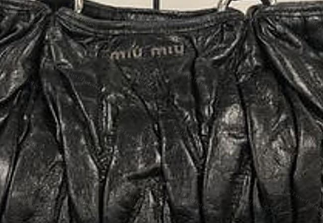 Gefälschtes Miu-Miu-Logo: „miu miu“ blind in ein Matelassé-Feld geprägt, der Abdruck flach und unruhig, die Buchstaben verschwommen und unterschiedlich tief