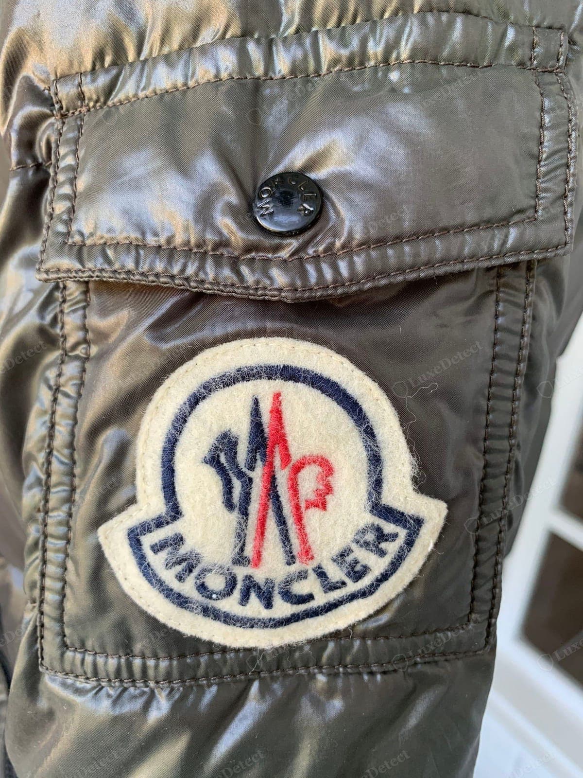 Patch sul braccio Moncler originale: la patch in feltro con il logo sulla manica, cucita in modo pulito, con il gallo e le lettere nitidi