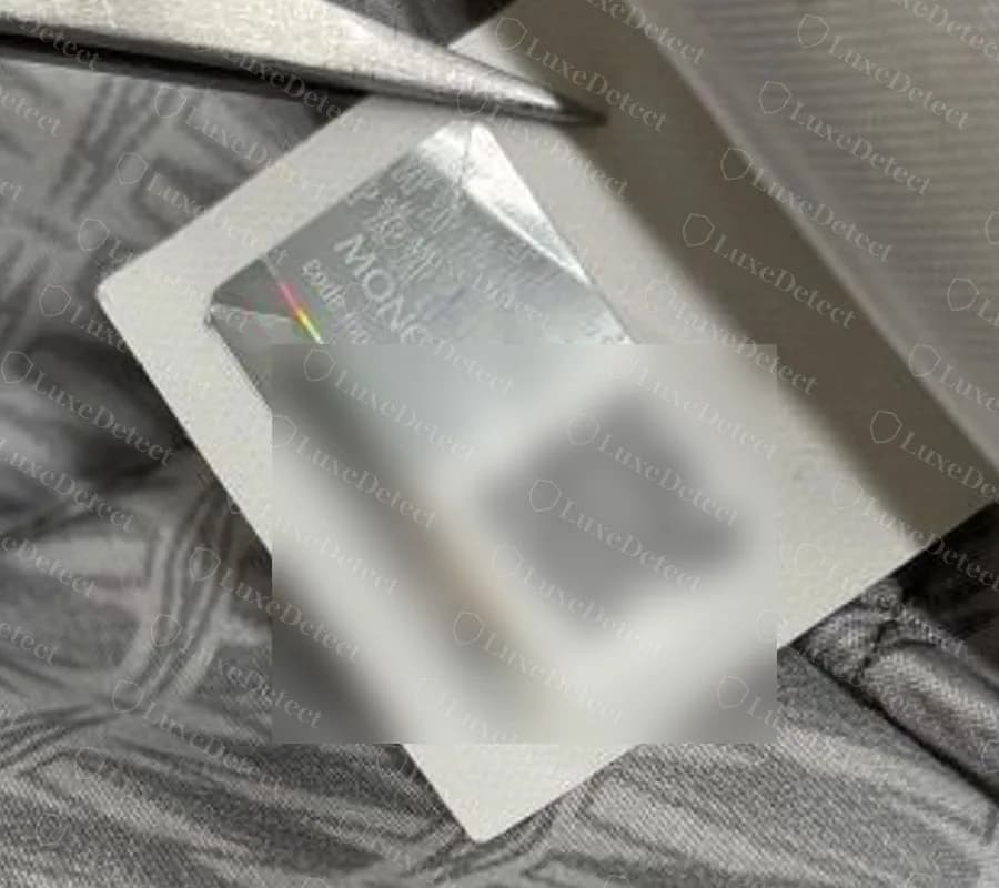A genuine Moncler holographic sticker label with a QR code, the B + letter + digits + letters format; the code and QR have been blurred