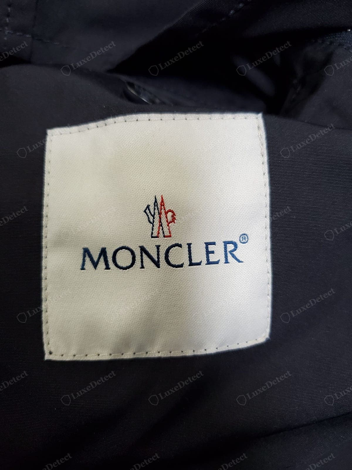 Genuine Moncler interior logo label — the woven "MONCLER" logo label inside, dense weave, sharp lettering
