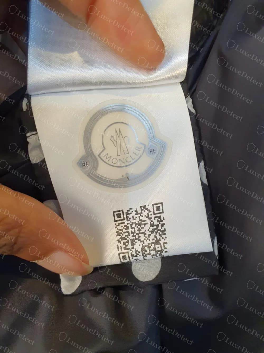 The front of a genuine Moncler RFID label: the logo is the chip antenna, with a QR code below it