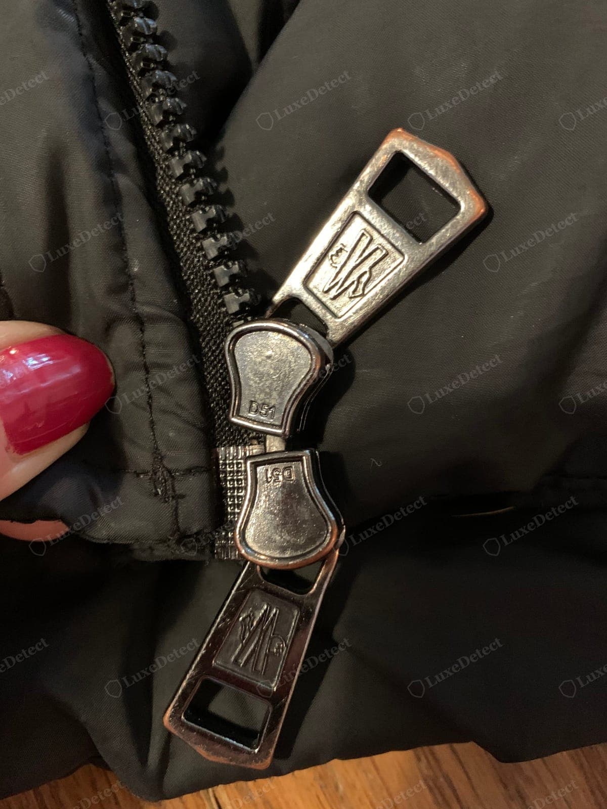Counterfeit Moncler zipper — an unbranded or crudely marked slider, a gritty action, a wrong maker