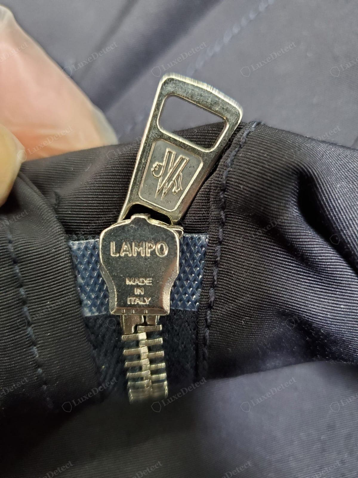 Cierre Moncler original: el reverso del tirador con la marca correcta del fabricante (a menudo Lampo o un equivalente de marca), con una acción suave
