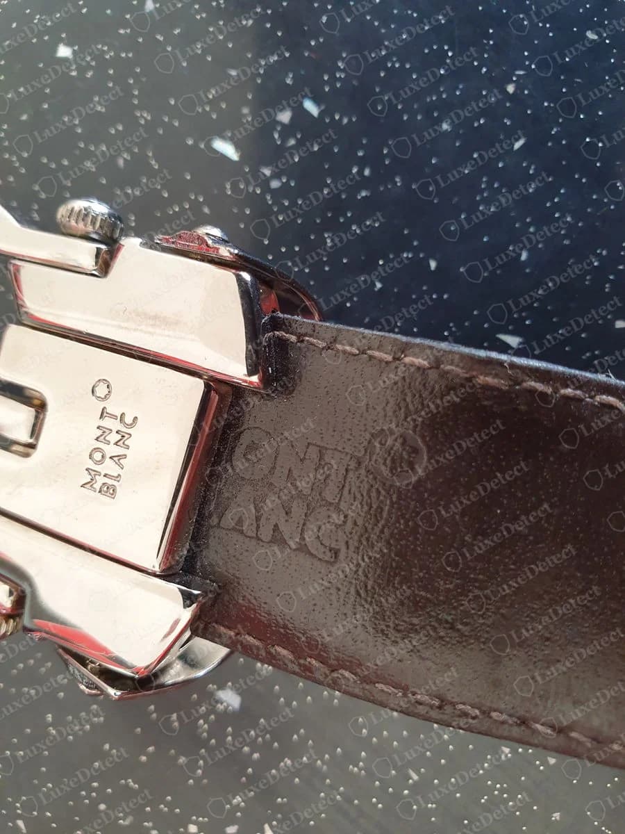 Genuine Montblanc belt: the reverse of a polished buckle stamped MONT BLANC with a star, beside the same wordmark pressed into the brown leather strap