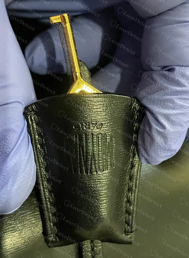Counterfeit Moynat Flori key holder embossed with the condensed MOYNAT logo, with a gold key