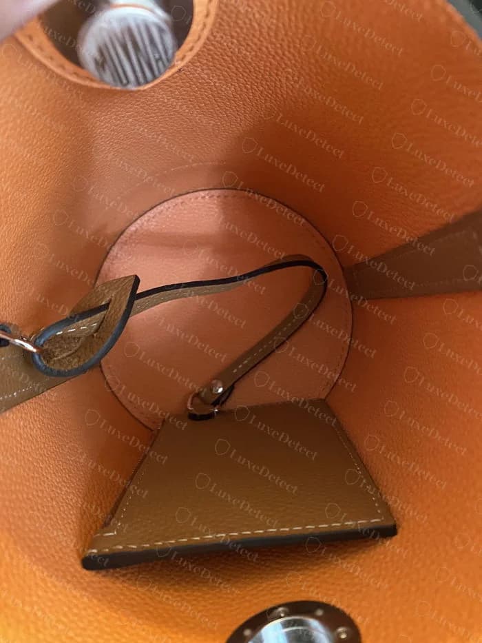 Moynat Réjane interior construction, gusseted bucket shape with a central zip pocket and leather strap keeper