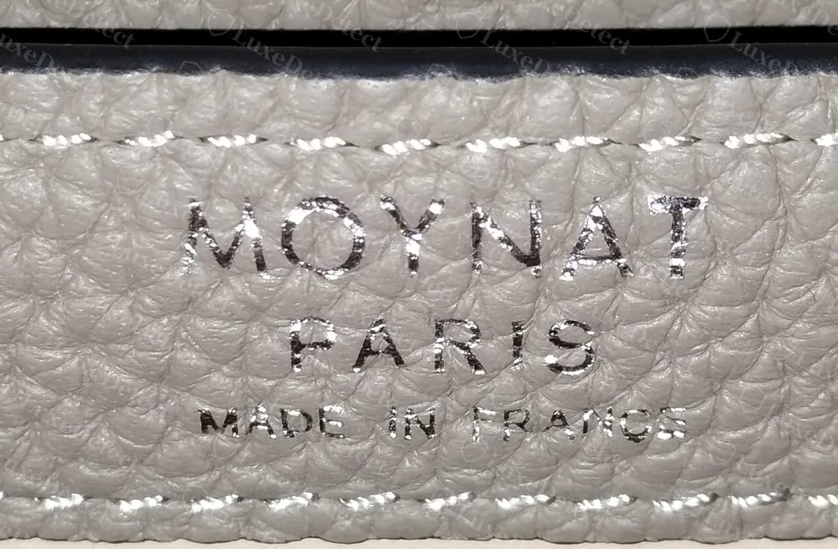 Sello interior de un Moynat Réjane falsificado con la leyenda MOYNAT PARIS MADE IN FRANCE en lámina plateada brillante y pesada con letras gruesas