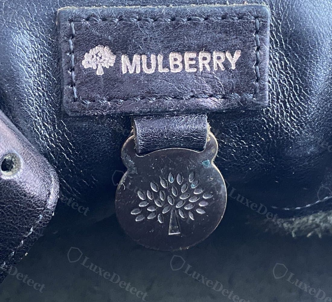 Counterfeit Mulberry padlock and tab from the same reference set — duller, less reflective brass and a flatter, less defined tree stamp by comparison